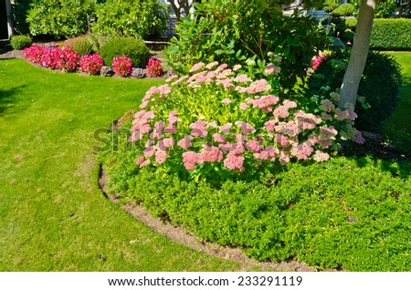 Flowers and nicely trimmed bushes in front of the house, front yard. Landscape design.