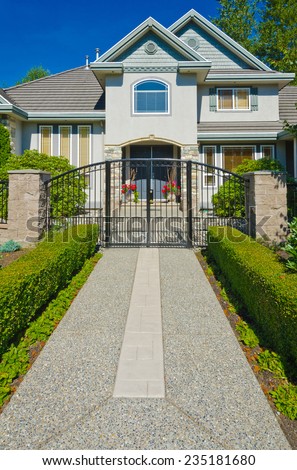 Entrance of big custom made luxury house with nicely landscaped front yard and long doorway in the suburbs of Vancouver, Canada.