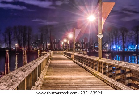 Fantastic view of the wooden pier, promenade, road, path in the park along the river ( ocean ) bank at night, dick time. Vancouver, Canada.