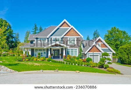 Big custom made luxury house with nicely landscaped and trimmed front yard and driveway to garage in the suburbs of Vancouver, Canada.