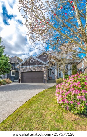Big custom made luxury house with nicely landscaped front yard, double doors garage and long and wide driveway in the suburbs of Vancouver, Canada. Vertical.