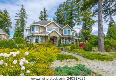 Custom built luxury house with nicely trimmed and landscaped front yard, lawn in a residential neighborhood. Vancouver, Canada.