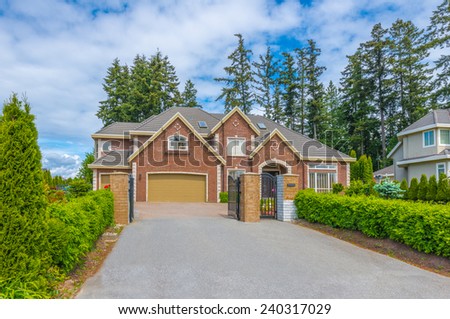 Custom built luxury house with nicely trimmed and landscaped front yard, lawn and wide driveway to the garage in a residential neighborhood. Vancouver Canada.