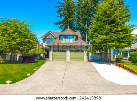 Custom built luxury house with nicely trimmed and landscaped front yard lawn and driveway to garage in a residential neighborhood. Vancouver Canada.
