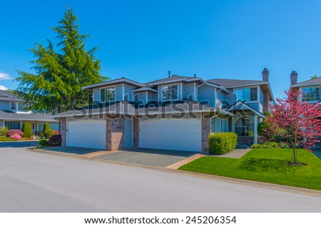 Custom built luxury house with nicely trimmed and landscaped front yard lawn and double doors garage in a residential neighborhood. Vancouver Canada.