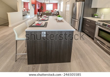 Nicely decorated kitchen counter table, iceland table and dining table and living room at the back. Interior design.