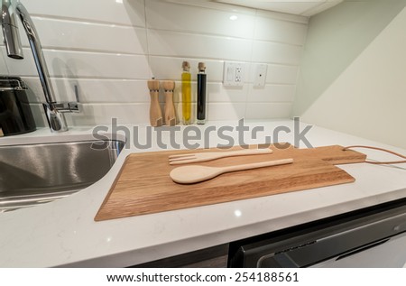 Cutting desk with wooden spoon and fork  and salt and pepper mills and oil and vinegar containers as a decorative element of the luxury modern kitchen. Interior design.