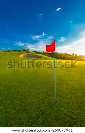 Red flag and sand bunker at the beautiful golf course at sunset, sunrise time. Vertical.