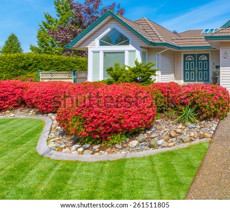 Nicely decorated front yard with flowers, stones and bushes as a decorative elements. Landscape design.