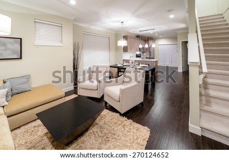 Luxury modern living suite : two chairs and living room, dining room and the kitchen at the back and the stairs to upper level.  Interior design.