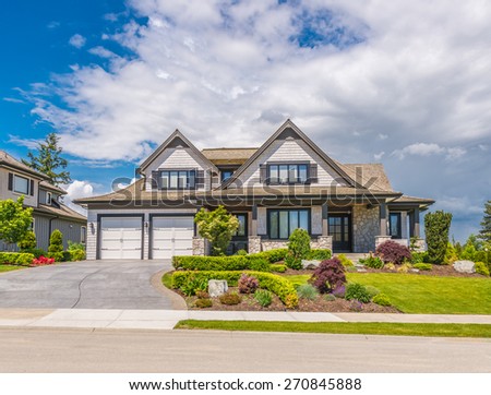 Big custom made luxury house with nicely landscaped front yard and  driveway to the garage in the suburb of Vancouver, Canada.