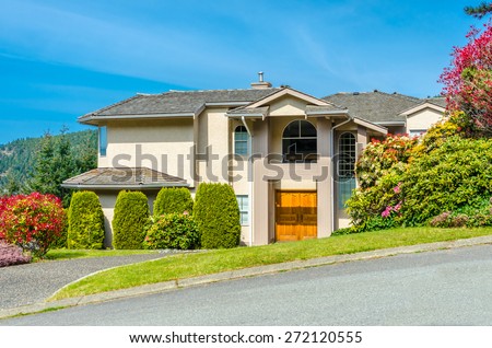 Big custom made luxury  house with nicely landscaped front yard and driveway to garage in the suburb of Vancouver, Canada.