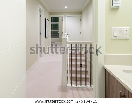 Corridor on the upper level of a house with the stairs and the room at the end. Interior design.