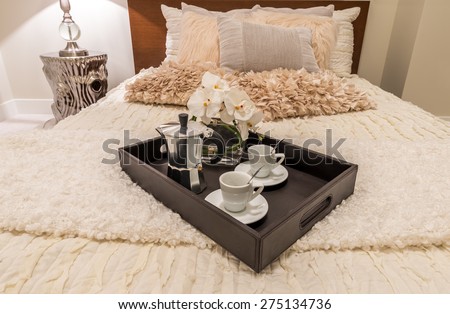Decorative tray with the coffee set on the bed in the luxury modern  bedroom. Interior design.