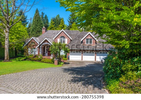 Custom built luxury house with nicely trimmed front yard, lawn and paved driveway to garage in a residential neighborhood. Vancouver Canada.