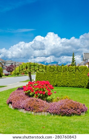 Trimmed bushes, flowers and stones in nicely decorated front yard, lawn of the house. Landscape design. Vertical.