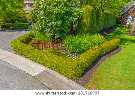 Trimmed bushes, flowers and stones in nicely decorated front yard, lawn of the house. Landscape design.