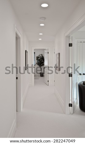 Corridor on the upper level of a house with some pictures on the walls and the room at the end. Interior design. Vertical.