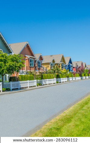 Nice and comfortable neighborhood, community. Some, line of homes behind the fence on empty street in the suburbs of the North America. Canada. Vertical.