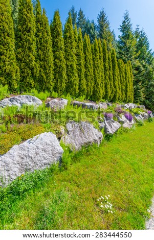 Nicely trimmed bushes, green fence  in front of the house, front yard. Keeps privacy and security. Landscape design. Vertical.