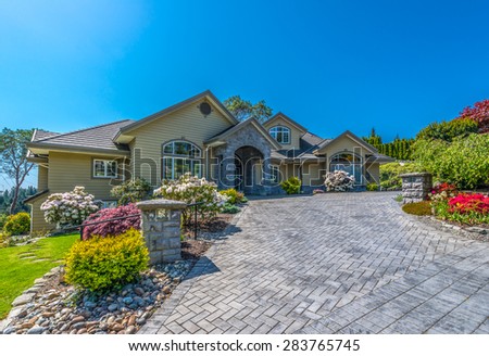 Custom built luxury house with nicely trimmed front yard, lawn and driveway to garage in a residential neighborhood. Vancouver. Canada.