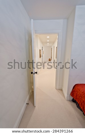 Corridor on the upper level of a house with some pictures on the walls and the room at the end. Interior design. Vertical.