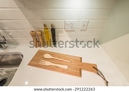 Cutting desk with wooden spoon and fork  and salt and pepper mills and oil and  vinegar containers as a  decorative element of the luxury modern kitchen. Interior design.