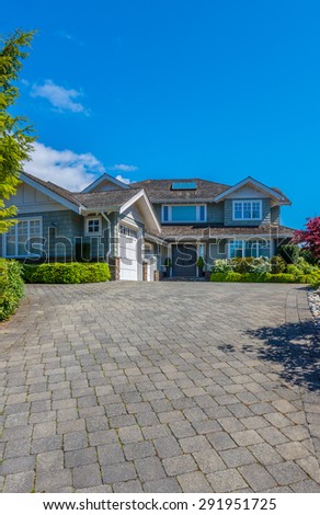 Big custom made luxury house with nicely landscaped front yard and paved driveway to garage in the suburbs of Vancouver, Canada. Vertical.