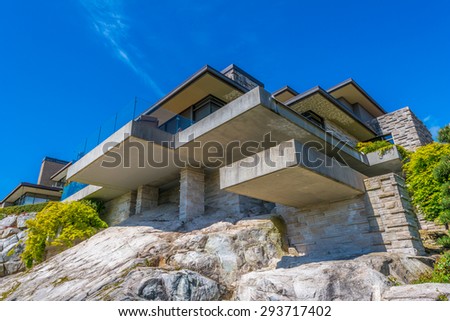 Big custom built luxury modern house on the rocks, cliff with nicely landscaped front yard in the residential neighborhood of Vancouver, Canada. Vertical.