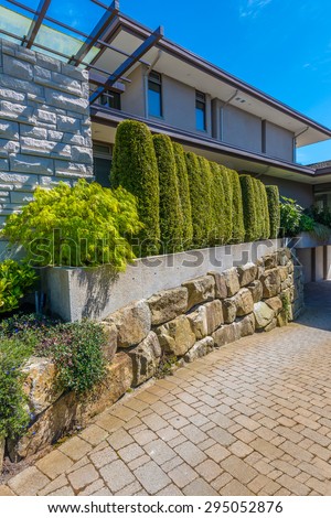 Flowers, stones and nicely trimmed bushes in front of the house, front yard. Landscape design. Vertical.
