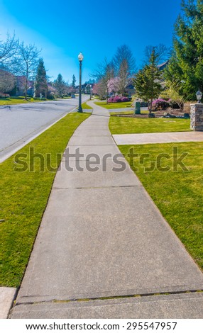 Nice and clean long, sidewalk, path at the empty street. Neighborhood scenery. Vertical.