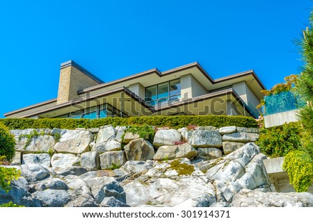 Big custom made luxury modern house on the rocks with nicely landscaped front yard in the suburbs of Vancouver, Canada.