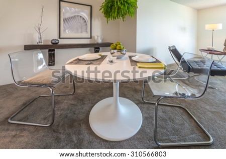 Nicely decorated dining table in the luxury modern kitchen with the living room at the back. Interior design.