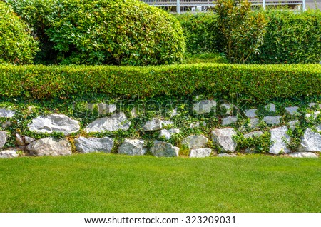 Nicely trimmed bushes, flowers and stones in front of the house, front yard. Landscape design.