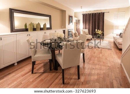 Luxury living suite with nicely decorated dining table, stylish mirror at the wall and the living room at the back.  Interior design.