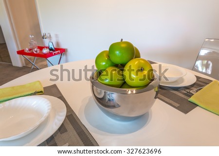 Nicely decorated dining table with some apples in the vase in the luxury modern dining room. Interior design.