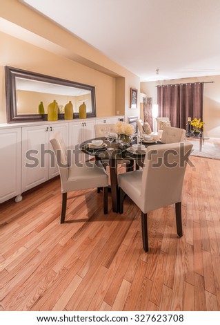 Luxury living suite with nicely decorated dining table, stylish mirror at the wall and the living room at the back.  Interior design. Vertical.
