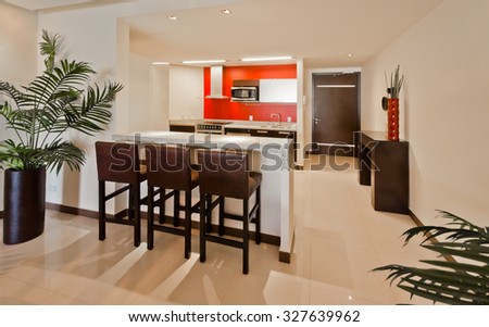 Nicely decorated kitchen counter table, iceland table, dining table and a modern kitchen at the back. Interior design.