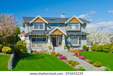 Big custom built luxury  home with nicely trimmed and landscaped front yard in the suburbs of Vancouver, Canada.
