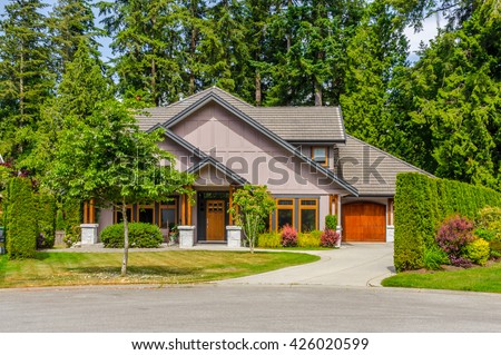 Custom built luxury house, with nicely trimmed and landscaped front yard, lawn and driveway to garage in a residential neighborhood. Vancouver Canada.