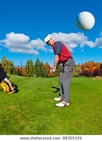 Golfer driving golf ball on beautiful golf course with deep blue sky and white clouds