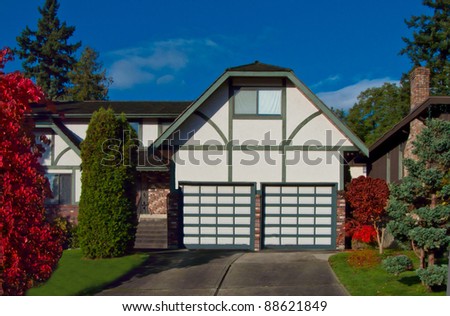 Two doors garage and a house with nice frontyard landscape in a sunny fall time
