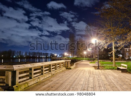 Fantastic view of the wooden trail,  promenade, road, path in the park along the river ( ocean ) bank at night, dick time. Vancouver, Canada
