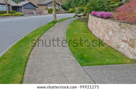 Nice and clean sidewalk and the empty street. Neighborhood scenery, landscape design.