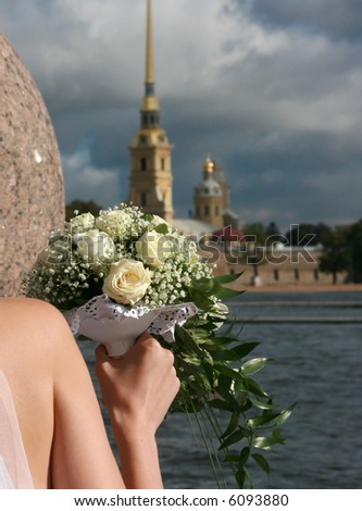 Bride holds bouquet of white roses. The Peter and Paul Fortress. St. Petersburg. Russia.