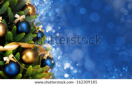 Magically decorated Christmas Tree with balls, ribbons and garlands on a blurred blue shiny, fairy and sparkling background, banner format