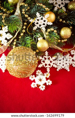 Christmas card with fir tree branch decorated with golden baubles, garlands and vintage snowflakes on a red background with copy space for your text