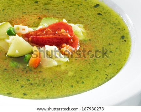 Hot vegetarian healthy soup with pesto sauce, noodles and vegetables in a round plate