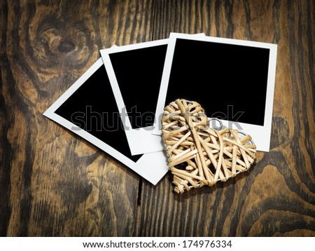 Retro style polaroid photo cards and vintage entwined heart on wooden background. Eco love concept. Space for your text.