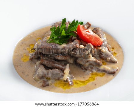 Delicious hot beef stroganoff with cream sauce served on a white plate. Isolated on white.